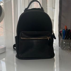 Mini black backpack with slight rip at the top.